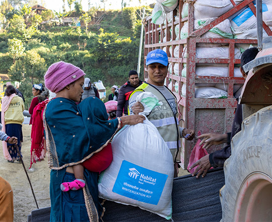 A Nepali woman with child receving winterization kit